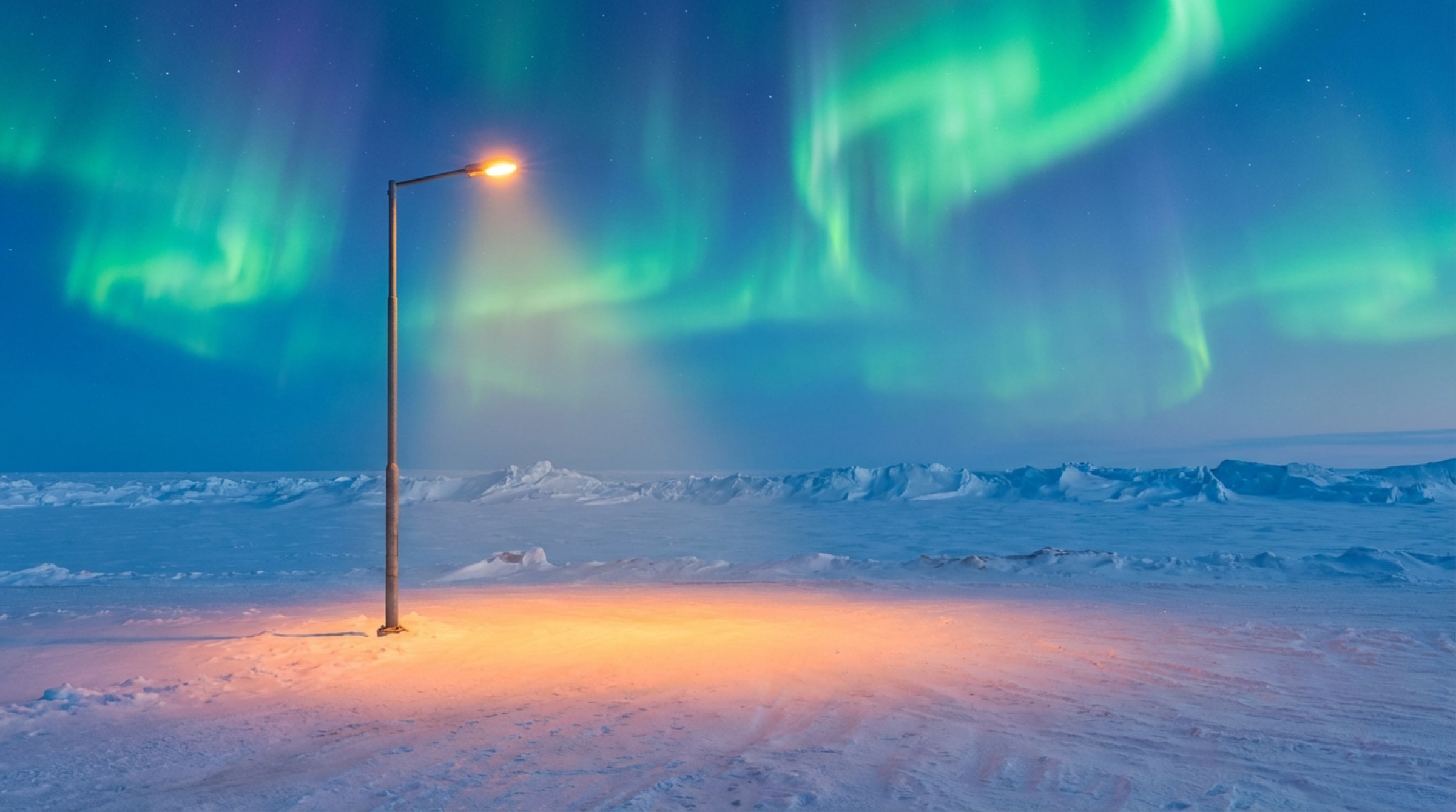 A street light illuminating snow under the northern lights